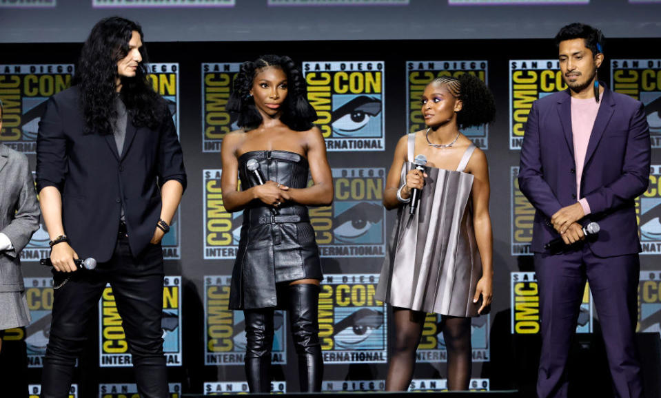 Four actors stand on the Comic-Con stage with microphones
