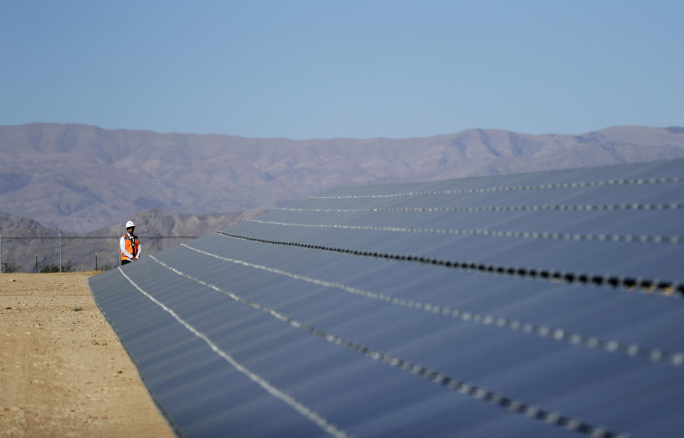 FILE - A man stands at the end of a solar panel array at a solar project site, Sept. 15, 2016, on the Moapa River Indian Reservation about 40 miles northeast of Las Vegas. The U.S. Department of Energy hopes to use nearly $15 million in federal grants to boost clean energy development at tribal colleges and universities around the country. (AP Photo/John Locher,File)