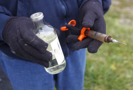 Hugh Byron, a retired dairy farmer, holds some of the medicine and a syringe that he says he formerly used to treat his cows on his farm in Hillsboro, Kentucky November 13, 2014. REUTERS/John Sommers II