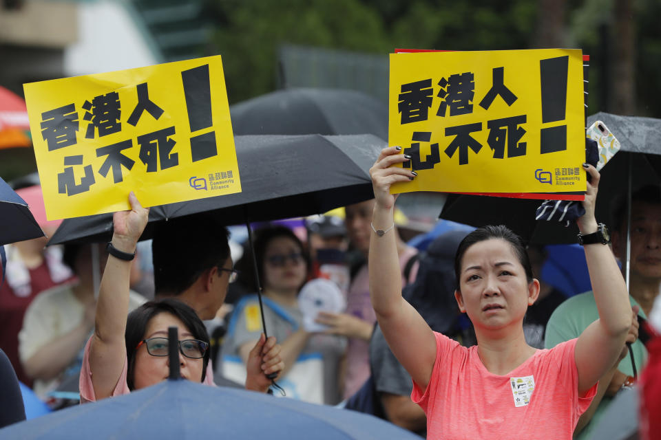 Participants hold up signs that read: "Hong Kongers won't give up!" during a rally in Hong Kong Sunday, Aug. 18, 2019. A spokesman for China's ceremonial legislature condemned statements from U.S. lawmakers supportive of Hong Kong's pro-democracy movement, as more protests were planned Sunday following a day of dueling rallies that highlighted the political divide in the Chinese territory. (AP Photo/Vincent Thian)