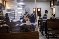 Ultra-Orthodox Jews wearing face masks during a morning prayer in a synagogue separated by plastic partitions, follow new government measures to help stop the spread of the coronavirus, in Bnei Brak, Israel, Friday, Sept 18, 2020. Israel is set to go back into a three-week lockdown later Friday to try to contain a coronavirus outbreak that has steadily worsened for months as its government has been plagued by indecision and infighting. The closures coincide with the Jewish High Holidays, when people typically visit their families and gather for large prayer services. (AP Photo/Oded Balilty)