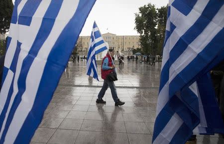 A man holding a Greek flag walks on central Syntagma square as the parliament is seen in the background, in Athens January 24, 2015. REUTERS/Marko Djurica