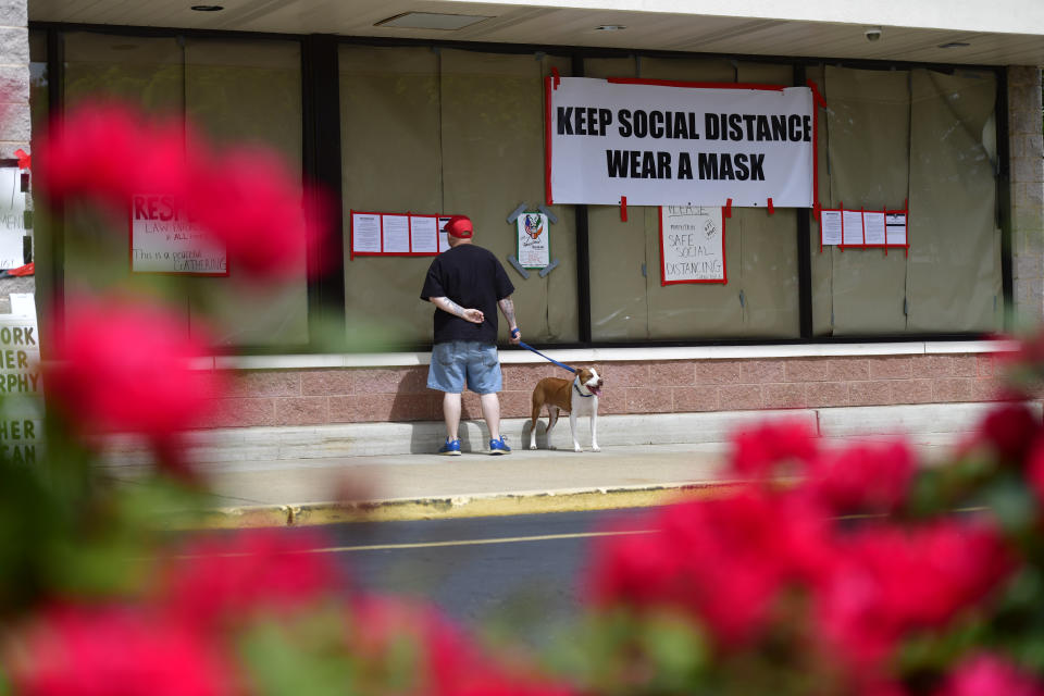 BELLMAWR, NJ - MAY 20: A man walking his dog reads notices outside of Atilis Gym below a placard stating "KEEP SOCIAL DISTANCE WEAR A MASK" on May 20, 2020 in Bellmawr, New Jersey. The gym has opened for the third consecutive day, defying the New Jersey Governor's mandate that many retail businesses stay closed due to the coronavirus pandemic.  (Photo by Mark Makela/Getty Images)