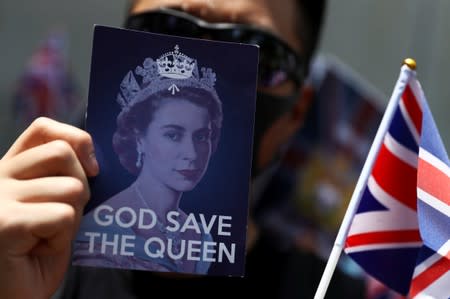 An anti-government protester holds up a Union Jack flag and a placard with a likeness of Queen Elizabeth at the British consulate General in Hong Kong