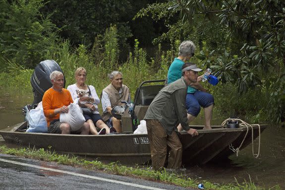 People arrive to be evacuated by members of the Louisiana Army National Guard near Walker, La., after heavy rains inundating the region.