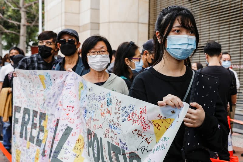 Supporters hold a banner to support pro-democracy activists as they queue up for a court hearing over the national security law outside West Kowloon Magistrates' Courts, in Hong Kong