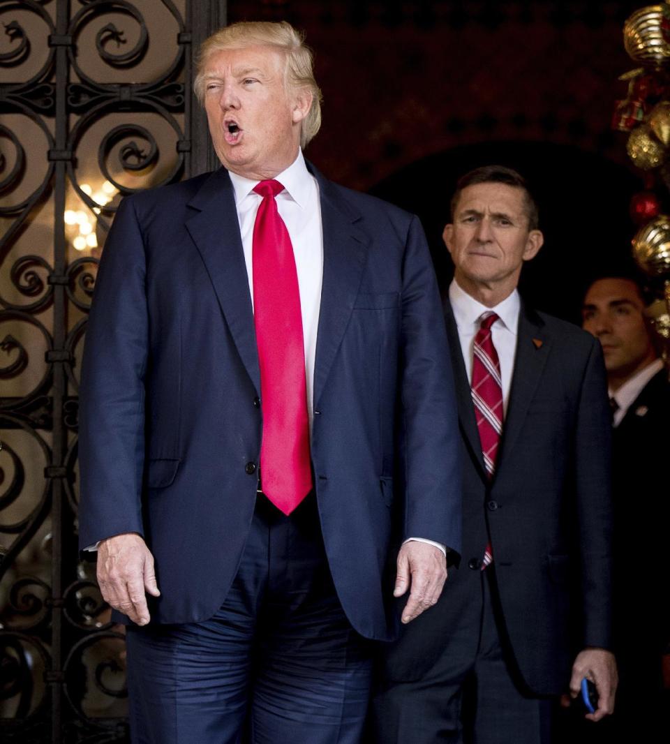 President-elect Donald Trump, left, accompanied by retired Gen. Michael Flynn, a senior adviser to President-elect Donald Trump, center, speaks to members of the media at Mar-a-Lago, in Palm Beach, Fla., Wednesday, Dec. 21, 2016. (AP Photo/Andrew Harnik)