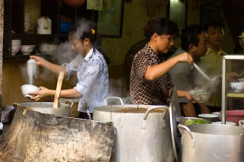 Dishing up pho at a restaurant in Hanoi - Credit: GETTY