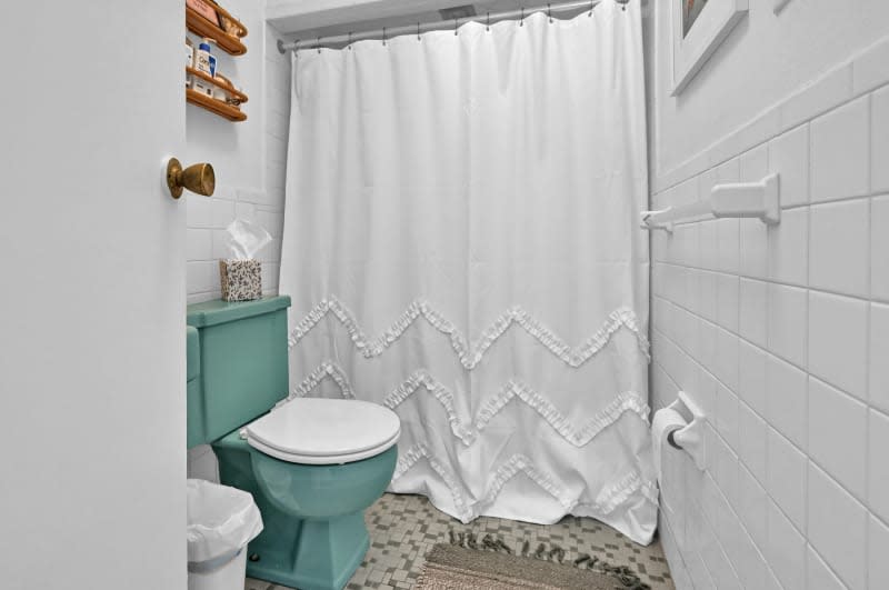 A bathroom with white tile and teal sink and toilet.