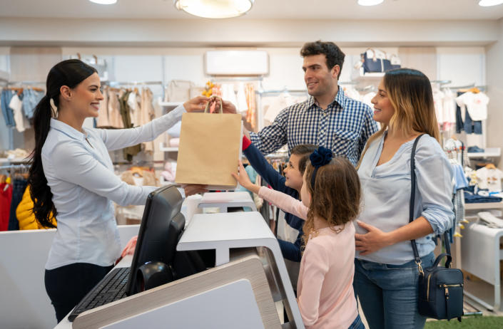 A sales associate handing a family their purchase
