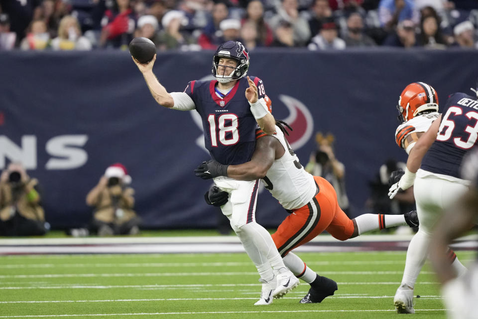 Houston Texans quarterback Case Keenum (18) throws as Cleveland Browns defensive end Za'Darius Smith (99) tackles during the first half of an NFL football game Sunday, Dec. 24, 2023, in Houston. (AP Photo/David J. Phillip)