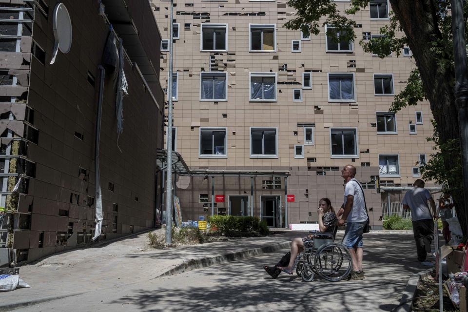 A man hauls a wheelchair with a girl in front of Okhmatdyt children's hospital hit by Russian missiles on Monday, in Kyiv, Ukraine, Tuesday, July 9, 2024. (AP Photo/Evgeniy Maloletka)