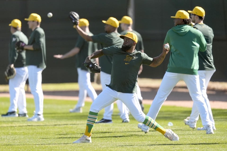 Oakland Athletics players warm up during a baseball spring training workout, Friday, Feb. 16, 2024, in Mesa, Ariz. (AP Photo/Matt York)