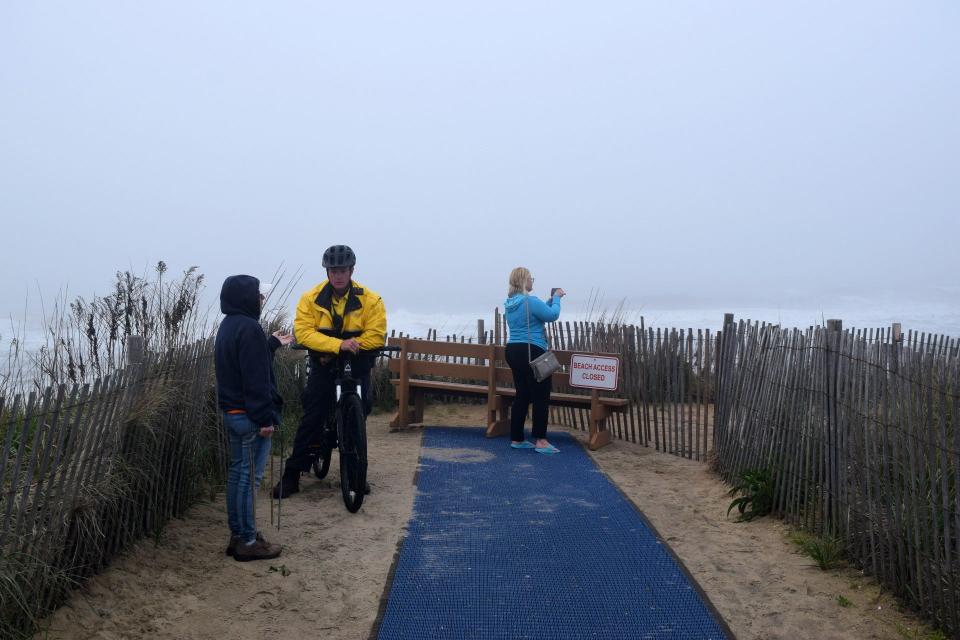 A police officer speaks to citizens atop a dune at Garfield Parkway in Bethany Beach. All dune crossings in Bethany Beach were closed May 13.