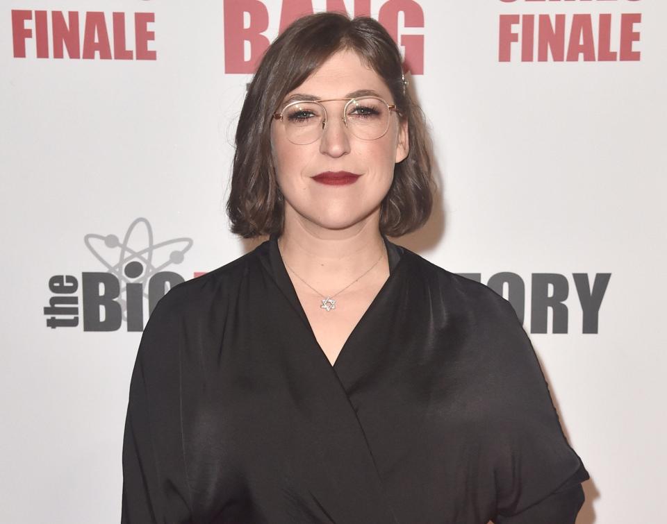 Mayim wears a black wrap top at an event