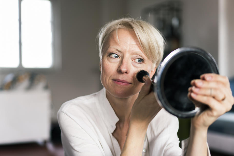 mature woman applying blush to skin