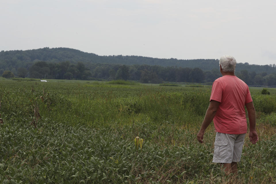 Jackie Murry, of New Albany Miss., views a stolen airplane that crash-landed in a field near Ripley, Miss., on Saturday, Sept. 3, 2022. Authorities say a man who stole a plane and flew it over Mississippi after threatening to crash it into a Walmart store faces charges of grand larceny and terroristic threats. Tupelo Police Chief John Quaka said Cory Wayne Patterson didn't have a pilot's license but had some flight instruction and was an employee of Tupelo Aviation. (AP Photo/Nikki Boertman)