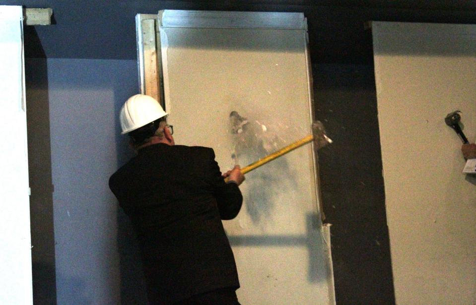 WEPA co-founder Rafael Torres breaking through a sheet of drywall, representing the beginning of construction on their allied health classrooms