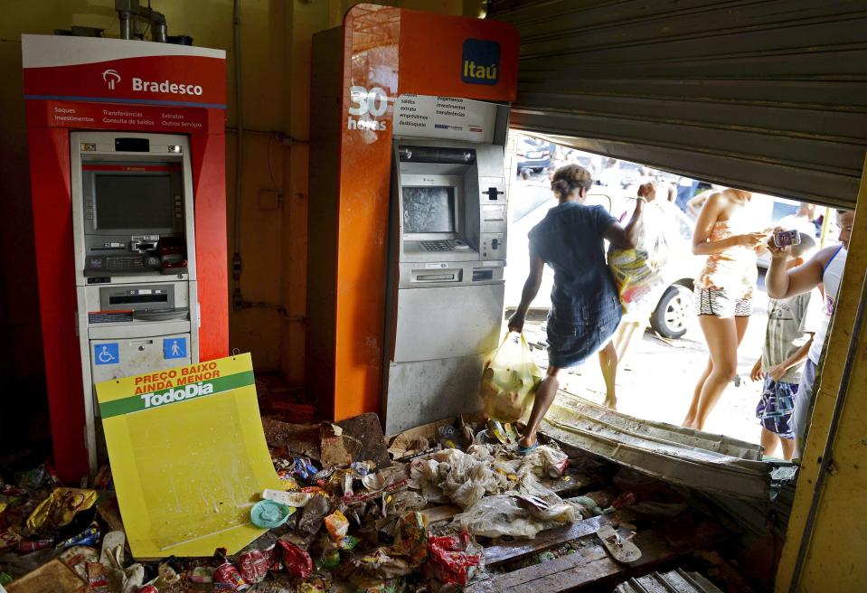 A woman carries bags of goods out of a supermarket that was looted in Salvador