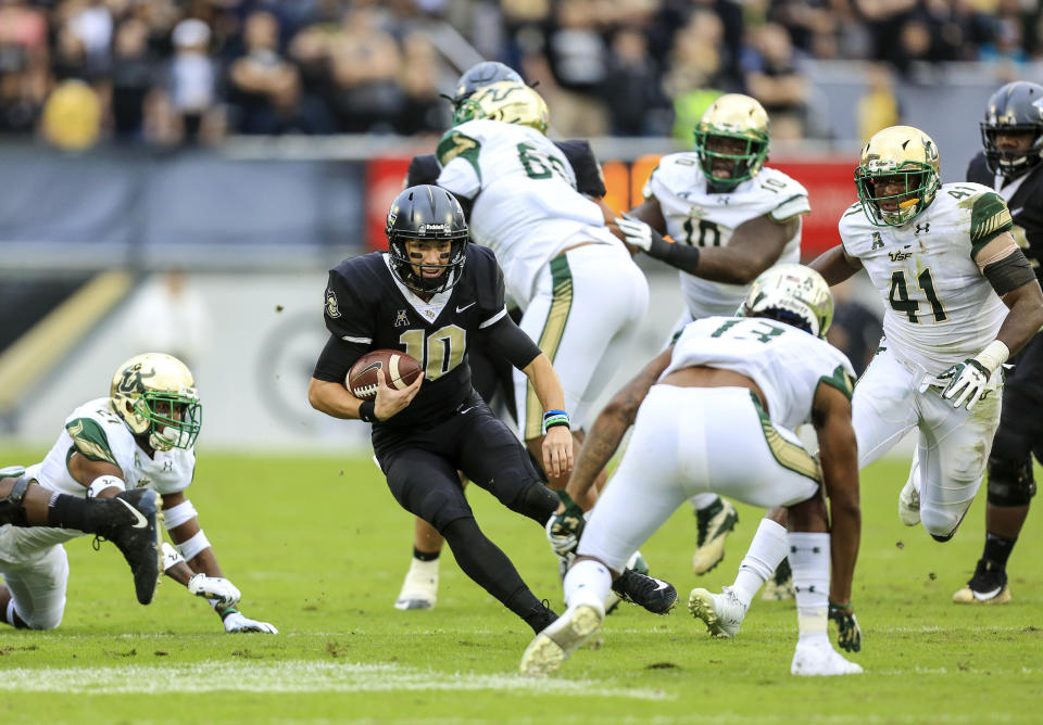 UCF quarterback Mckenzie Milton (10) runs the ball, looking to evade South Florida safety Tajee Fullwood (13) at Spectrum Stadium in Orlando, Fla., on Friday, Nov. 24, 2017. (Jacob Langston/Orlando Sentinel/TNS)