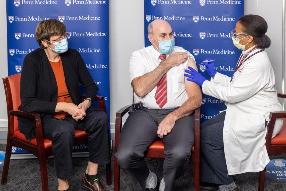 Drew Weissman, center, receives his first dose of the COVID-19 vaccine, with Katalin Karikó, left.