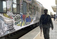 A police officer walks past a train at the train station in Abuja, Nigeria, Monday, Dec. 5, 2022. Train service in Nigeria's capital city resumed on Monday, eight months after assailants attacked a train with explosives and gunfire, killing seven people and abducting dozens of passengers. (AP Photo/Chinedu Asadu)