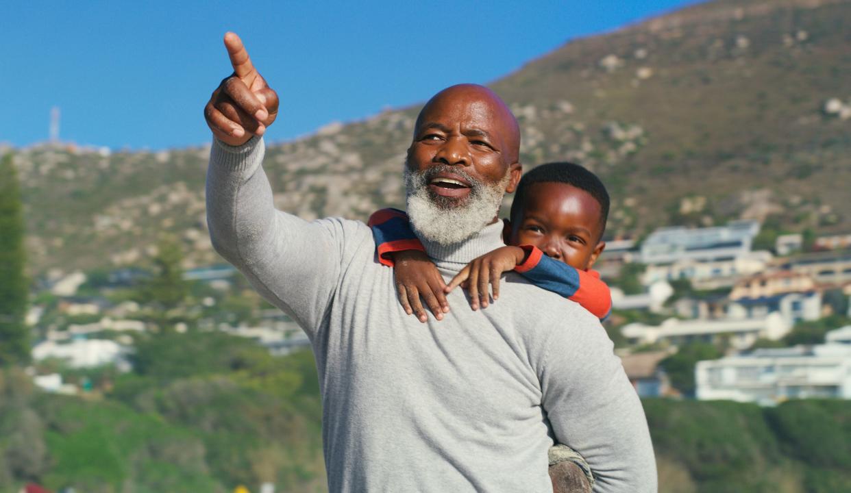 Cropped shot of a senior man pointing at something while giving his cute grandson a piggyback on the beach