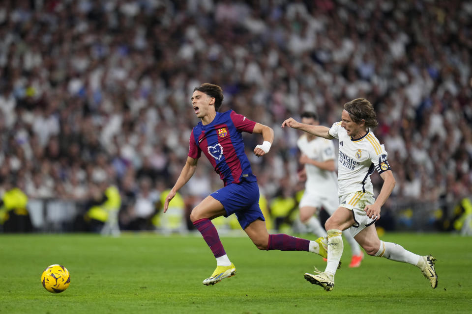 Barcelona's Joao Felix, left, is fouled by Real Madrid's Luka Modric during the Spanish La Liga soccer match between Real Madrid and Barcelona at the Santiago Bernabeu stadium in Madrid, Spain, Sunday, April 21, 2024. (AP Photo/Manu Fernandez)