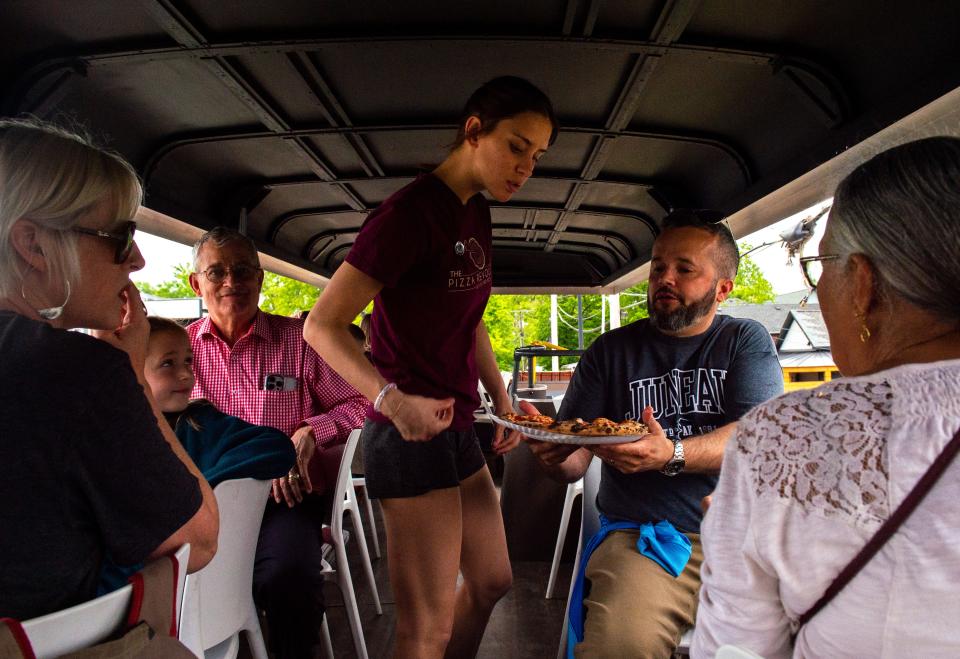 Sophie Peckeneaugh, center, delivers David Hayes’s order on the second floor of a double decker bus run by The Pizza Revolution during First Friday in Haynie’s Corner Arts District in Evansville, Ind., Friday, May 5, 2023.