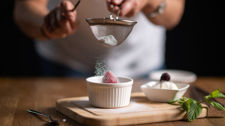 Person dusting powdered sugar