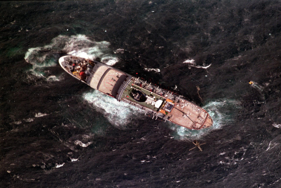 FILE — In this Aug. 4, 1991 file photo taken by South African photographer John Parkin, a rescue helicopter hovers over the sinking Greek luxury liner off the east coast of South Africa Parkin, who covered the country's anti-apartheid struggle, its first democratic elections, and the presidency of Nelson Mandela, has died Monday Aug. 23, 2021, at the age of 63 according to his daughter. (AP Photo/John Parkin/File)
