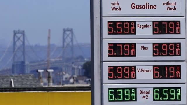 The San Francisco-Oakland Bay Bridge rises behind the price board of a gas station in San Francisco.