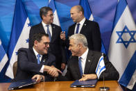 Israeli Prime Minister Naftali Bennett, back right, and Honduran President Juan Orlando Hernandez, speak as Israeli Foreign Minister Yair Lapid, front right, and Honduran Foreign Minister Lisandro Rosales shake hands after signing agreements between their two countries at the prime minister's office, in Jerusalem, Thursday, June 24, 2021. (Heidi Levine/Pool via AP).