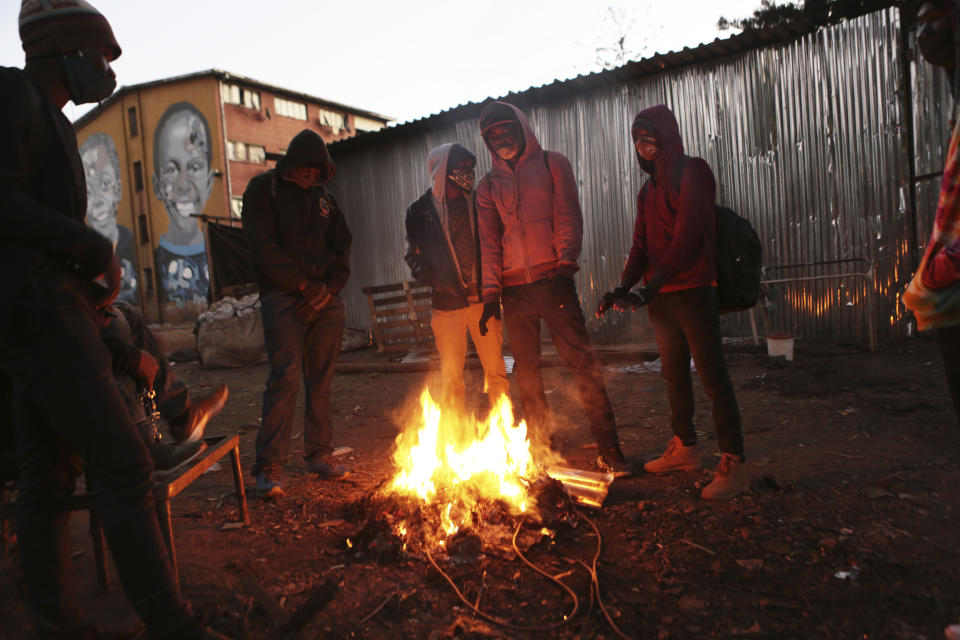 A group of people gather around a fire in a poor neighborhood in Harare, Monday, July 20, 2020. Zimbabwe’s finance minister says the country's economy is expected to shrink by 4.5% this year, although others say it will contract even more, as the effects of the coronavirus and a drought take a toll on the struggling southern African nation. ( AP Photo/Tsvangirayi Mukwazhi)