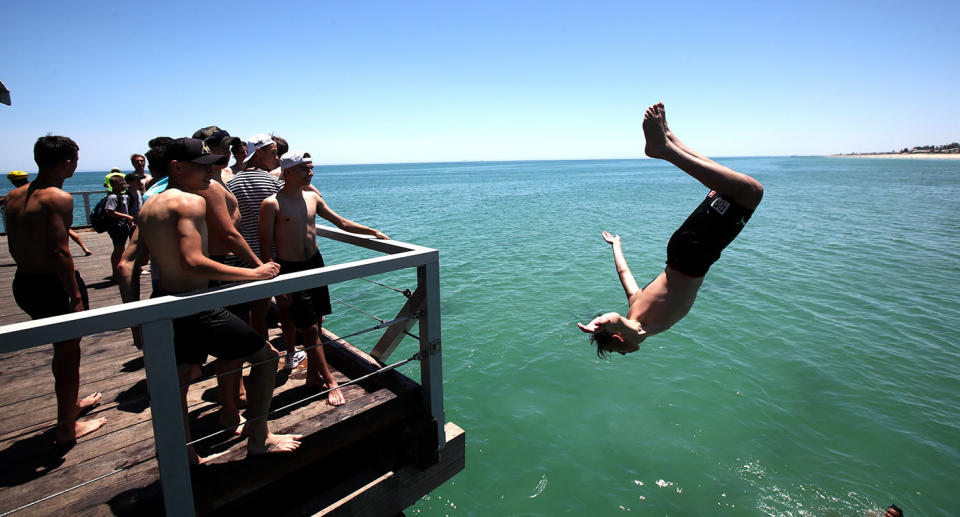 Adelaide teens escape the scorching heat at Henley Beach jetty. Image: AAP