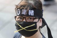 A Taiwanese woman wears a headband with a slogan "Anti-poisoned pork" during a protest in Taipei, Taiwan, Sunday, Nov. 22. 2020. Thousands of people marched in streets on Sunday demanding the reversal of a decision to allow U.S. pork imports into Taiwan, alleging food safety issues. (AP Photo/Chiang Ying-ying)