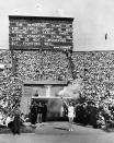 FILE - In this July 29, 1948 file photo, British athlete John Mark holds the Olympic Flame aloft in salute, beneath a quotation from Baron Pierre de Coubertin, founder of the modern games, before making his circuit of the Olympic track during the opening ceremony of the XIV Olympiad, in Wembley Stadium, London. London was still cleaning up bombing damage from World War II when it staged the Olympics in 1948. Britain was also struggling financially; food, clothing and gas were still being rationed. The athletes had to bring their own towels and, with housing in short supply, were accommodated in schools and Royal Air Force camps. The games were organized in less than two years, and despite the tiny budget it was a success, its legacies including greater sporting opportunities for women. (AP Photo, File)