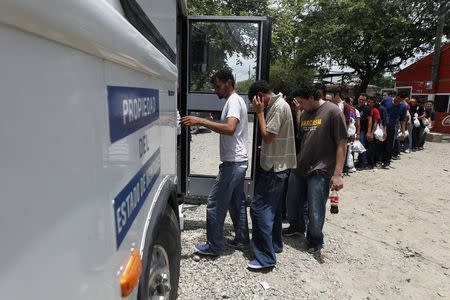 Deportees board a bus outside the Care Center for Returning Migrants (CAMR) after arriving on an immigration flight from the U.S., at the international airport in San Pedro Sula June 27, 2014. REUTERS/Jorge Cabrera