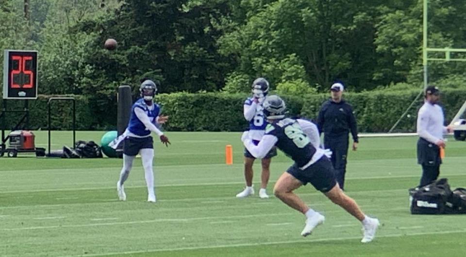 With new offensive coordinator Ryan Grubb (right, in all blue with a white cap) watching, Geno Smith (7) throws to rookie tight end Jack Westover from the University of Washington in the second practice of Seattle Seahawks NFL organized team activities (OTAs) at team headquarters in Renton May 23, 2024. Backup quarterback Sam Howell (6) is waiting his turn.