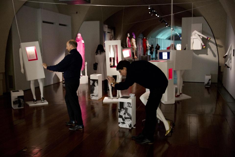 Men takes pictures of items by different designers displayed at the press view of the "Isabella Blow: Fashion Galore!" exhibition in London, Tuesday, Nov. 19, 2013. The exhibition, which runs from November 20 to March 2, celebrates the life and wardrobe of the late British patron of fashion and art who discovered many young fashion design talents. (AP Photo/Matt Dunham)