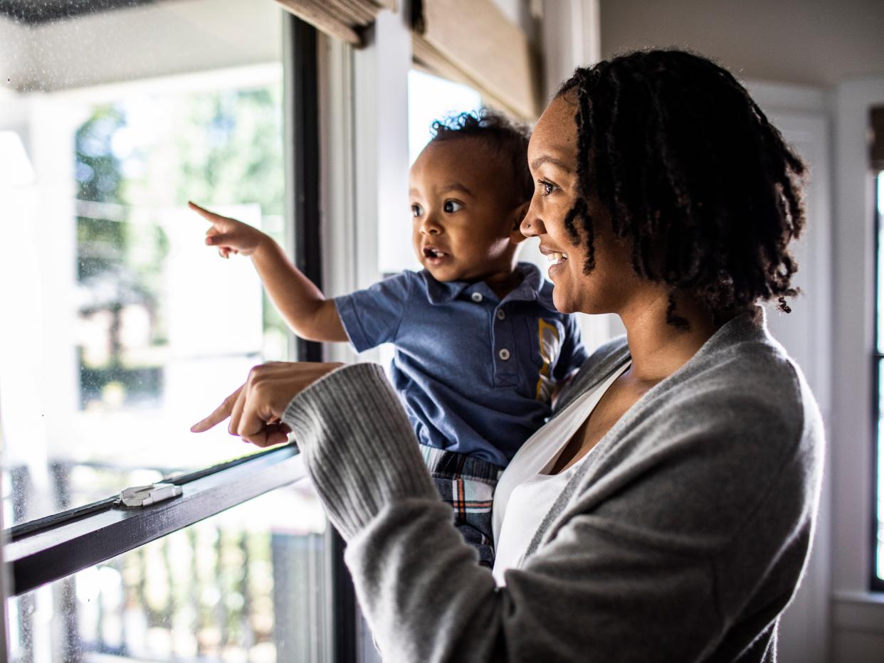 Woman and toddler looking out of home window