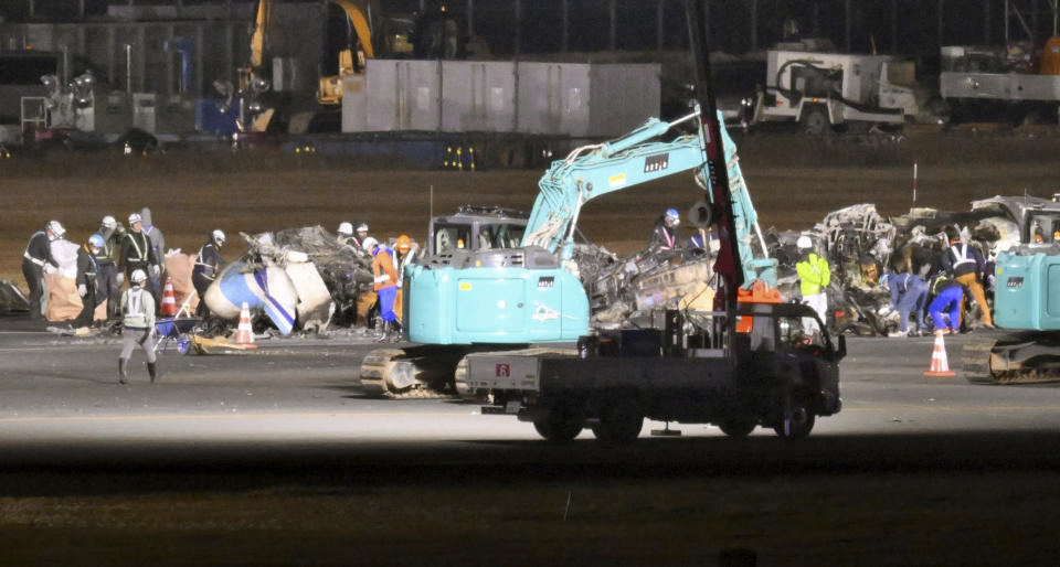 Officials and workers start removing the burnt Japanese coast guard aircraft at Haneda airport on Thursday, Jan. 4, 2024, in Tokyo, Japan. A transcript of communication between traffic control and two aircraft that collided and burst into flames at Tokyo’s Haneda Airport showed that only the larger Japan Airlines passenger flight was given permission to use the runway where a coast guard plane was preparing for takeoff. (Kyodo News via AP)