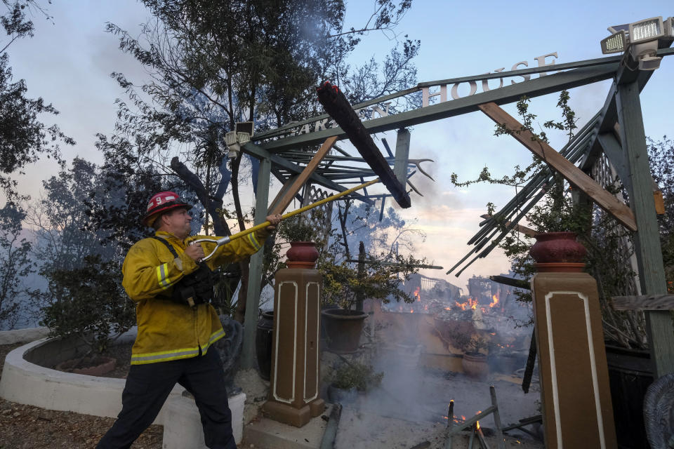 A firefighter works on a burning house as the South Fire burns in Lytle Creek, San Bernardino County, north of Rialto, Calif., Wednesday, Aug. 25, 2021. (AP Photo/Ringo H.W. Chiu)