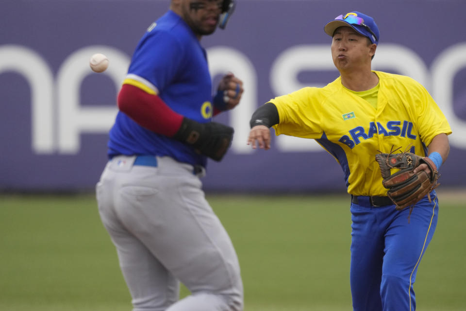 Brazil's Felipe Mizukosi throws the ball to first base to complete a double play during the baseball gold medal game against Colombia, at the Pan American Games in Santiago, Chile, Saturday, Oct. 28, 2023. (AP Photo/Moises Castillo)