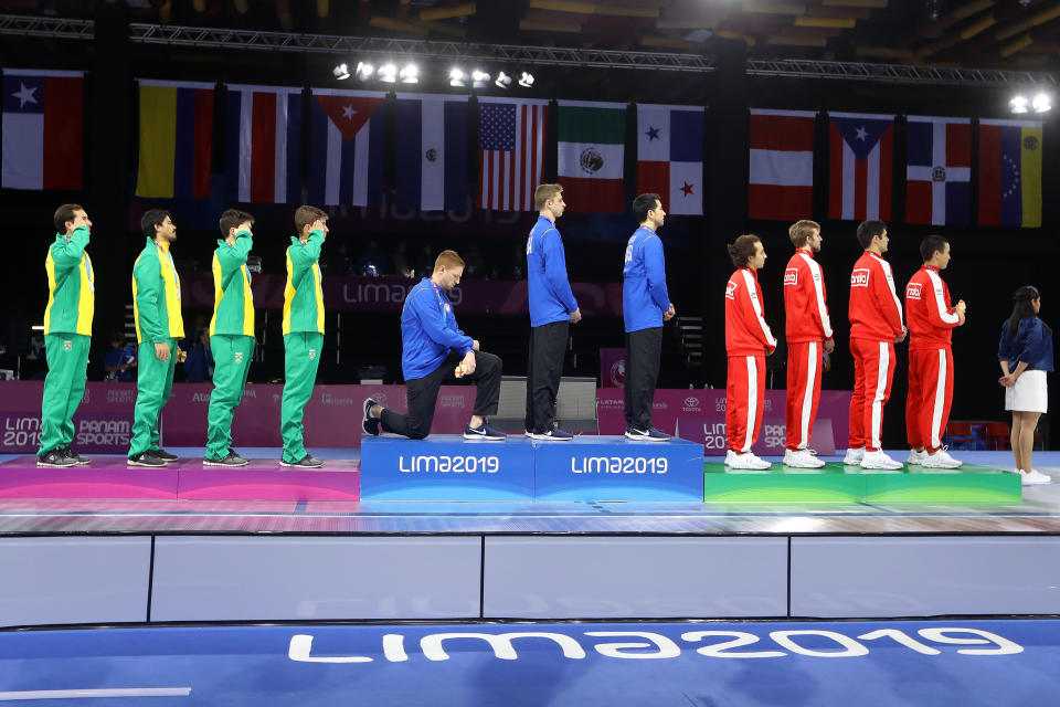 LIMA, PERU - AUGUST 09: Gold medalist Race Imboden of United States  takes a knee during the National Anthem Ceremony in the podium of Fencing Men's Foil Team Gold Medal Match Match on Day 14 of Lima 2019 Pan American Games at Fencing Pavilion of Lima Convention Center on August 09, 2019 in Lima, Peru. (Photo by Leonardo Fernandez/Getty Images)