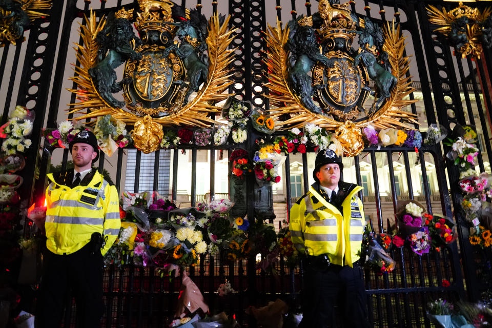 Police officers stand amongst floral tributes left outside Buckingham Palace in central London, following the announcement of the death of Queen Elizabeth II. (Photo by Victoria Jones/PA Images via Getty Images)