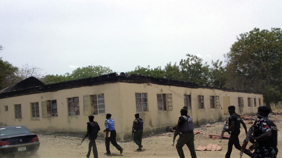 FILE - Security walk past the burned government secondary school Chibok where gunmen abducted more than 200 students in Chibok, Nigeria, Monday, April, 21. 2014. In Nigeria, Africa's most populous country, the mass abduction of Chibok schoolgirls a decade ago marked a new era of fear even as nearly 100 of the girls remain in captivity. An array of armed groups now focus on abducting schoolchildren, seeing in them a lucrative way to fund other crimes and control villages in the nation's mineral-rich but poorly-policed northwestern region. (AP Photo/ Haruna Umar, File)