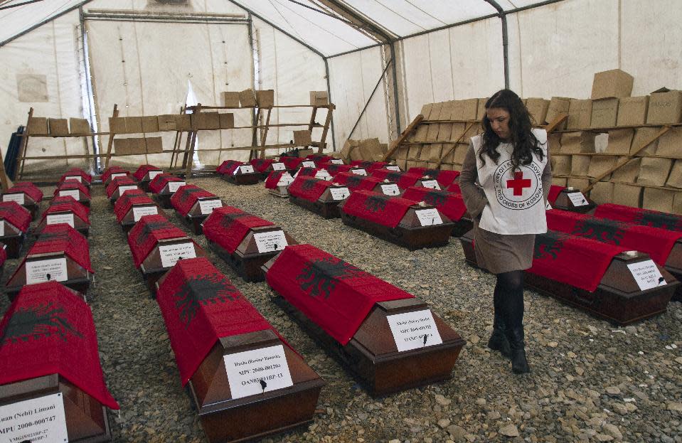 A Kosovo Red Cross volunteer looks at 46 coffins draped with Albanian flags containing the remains of ethnic Albanians killed during the 1998-99 Kosovo war in capital Pristina on Monday, March 24, 2014. The victims were killed in two separate rampages by Serbs forces in western Kosovo just days after NATO began a bombing campaign to stop Serbia’s onslaught on separatist ethnic Albanians on March 1999. (AP Photo/Visar Kryeziu)