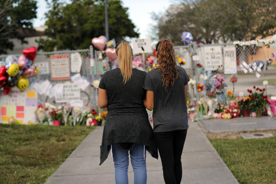 FILE- In this Feb. 19, 2018, file photo Sara Smith, left, and her daughter Karina Smith visit a makeshift memorial outside the Marjory Stoneman Douglas High School, where 17 students and faculty were killed in a mass shooting in Parkland, Fla. There have been more than 415 incidents of gunfire on U.S. school grounds since 2013, according to Every Town for Gun Safety, a nonprofit aimed at reducing domestic gun violence. Last year’s carnage at Marjory Stoneman Douglas High School surpassed the 1999 Columbine High School massacre as the deadliest high school shooting in U.S. history. (AP Photo/Gerald Herbert, File )