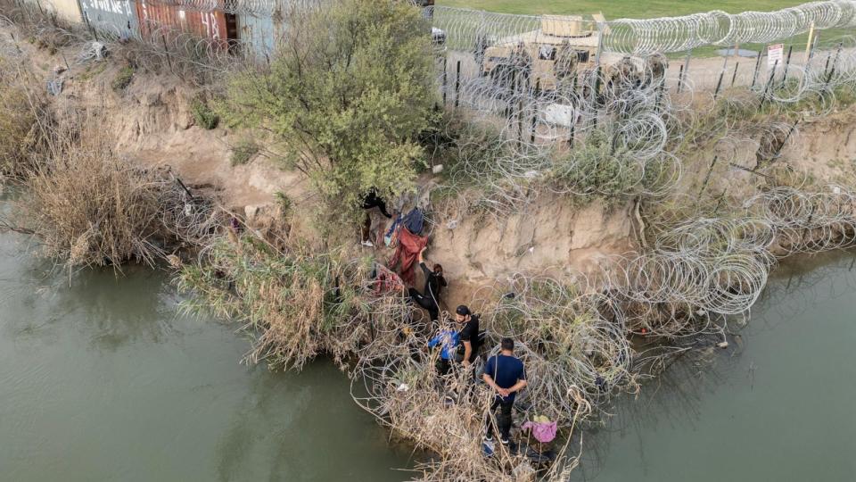 PHOTO: A group of migrants attempt to go through a wire fence on the banks of the Rio Grande river as members of U.S. National Guard stand on the other side of the fence in Eagle Pass, Texas, on Feb. 27, 2024. (Go Nakamura/Reuters)